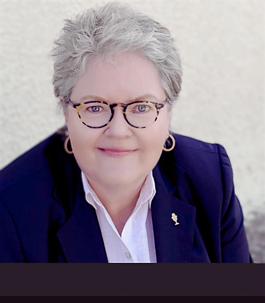 Lois Creamer is a white woman with short grey hair and glasses.