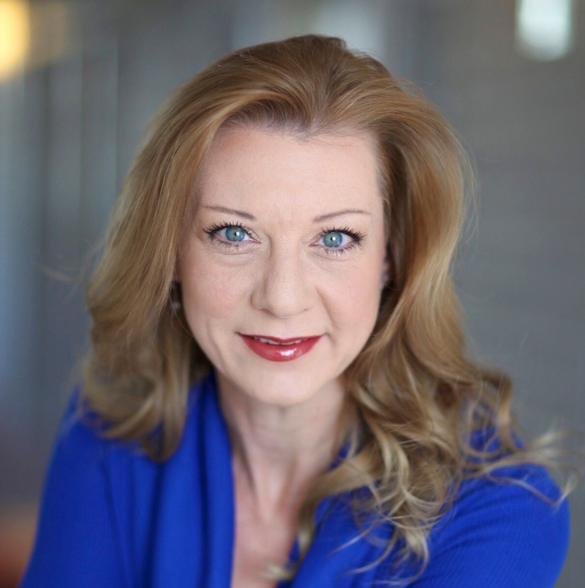 Susie Schaefer is a white woman with long blond hair and blue eyes, wearing a blue shirt.