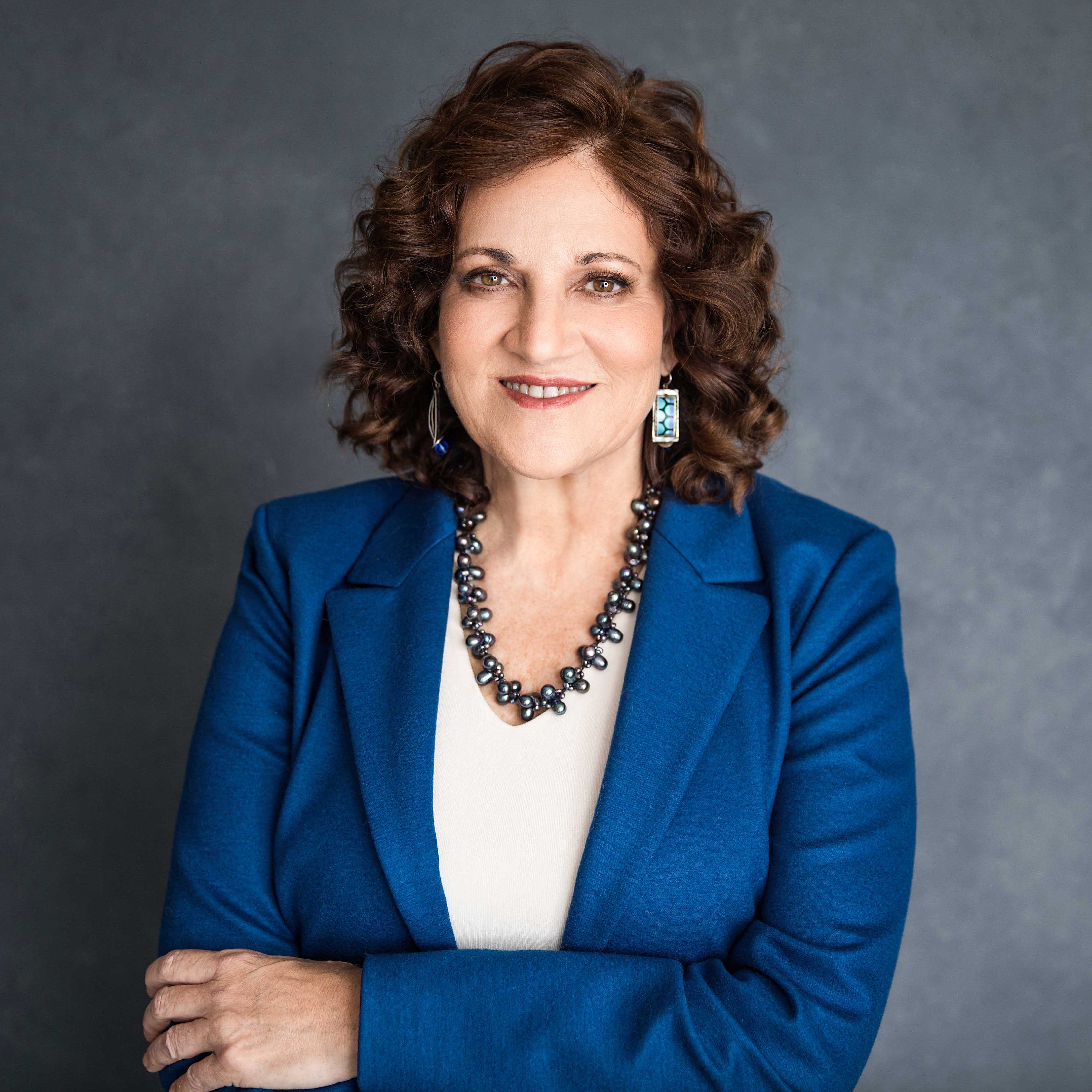 Linda Popky is a white woman with shoulder length brown hair and a big smile