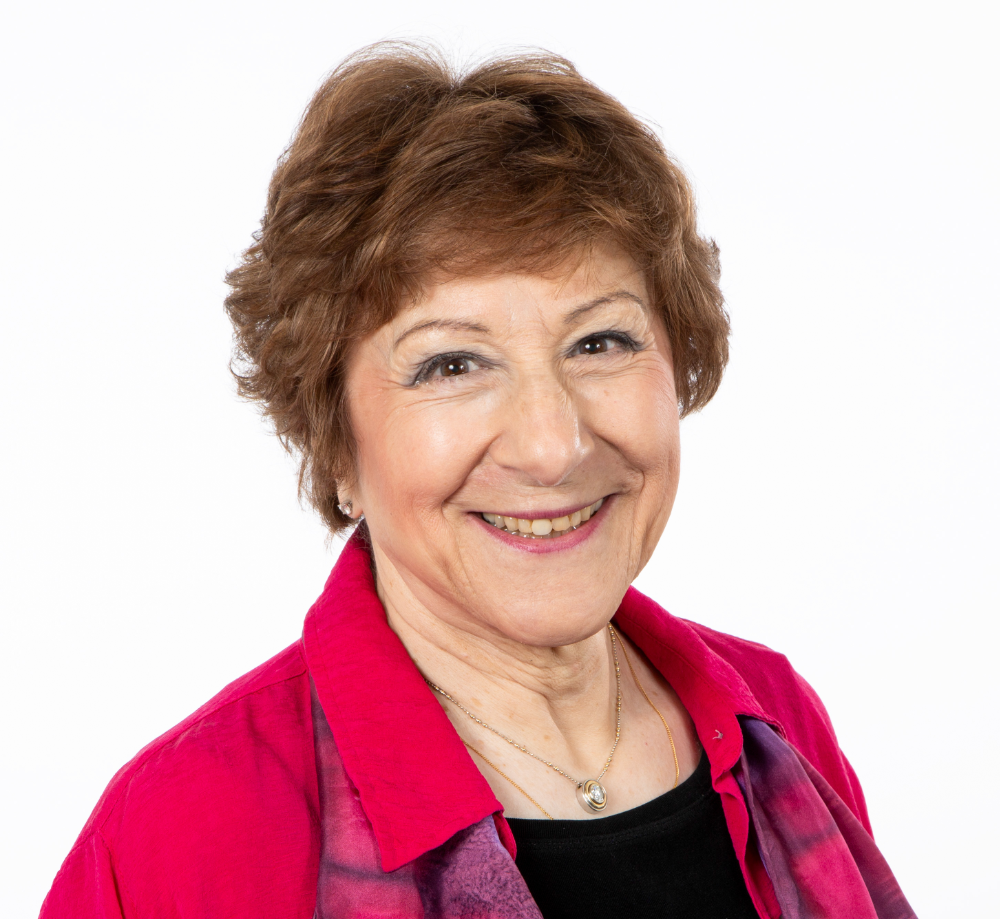 Susan Friedmann is a white woman with short brown hair and a big smile
